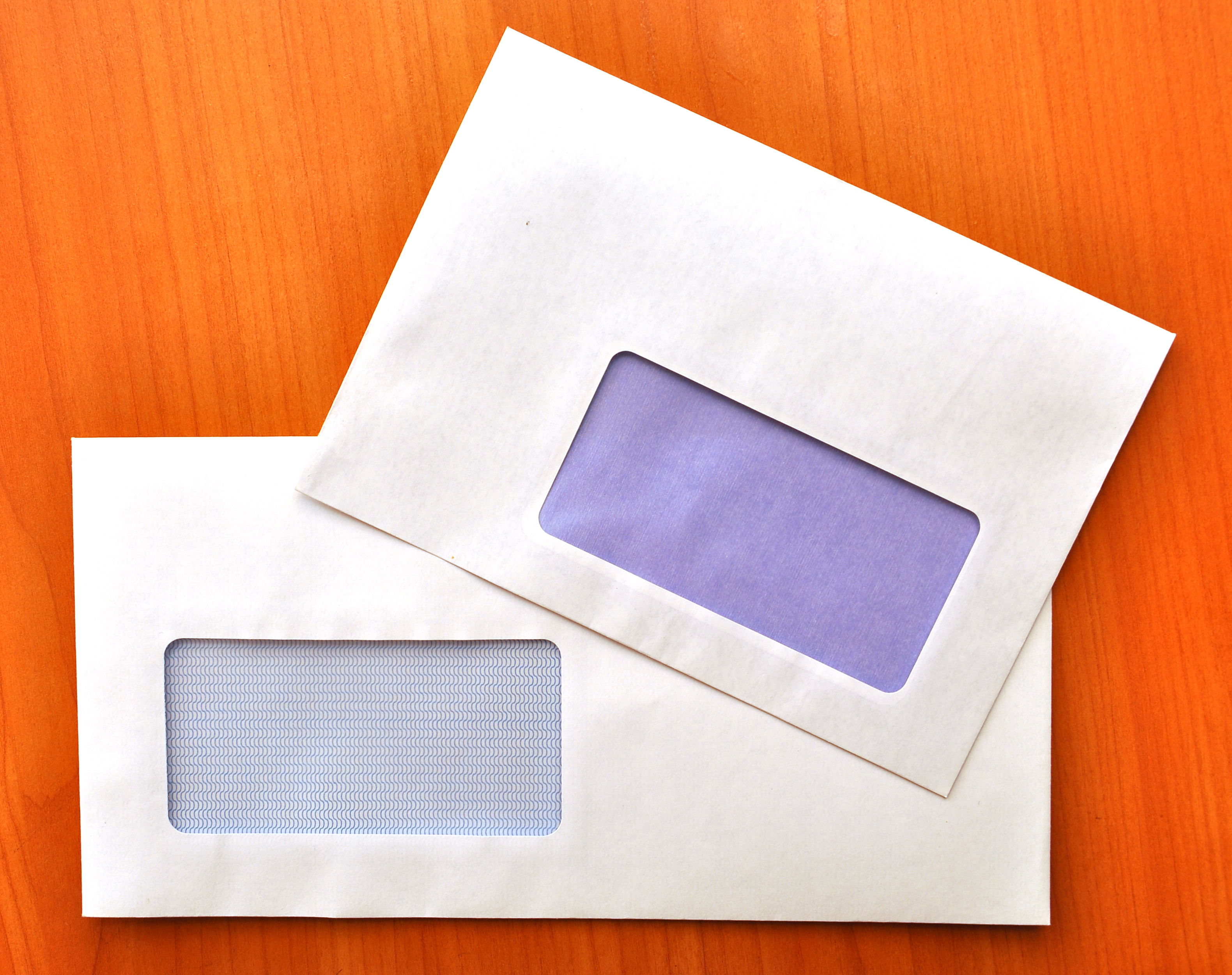 Two empty, letter-sized envelopes against a wood grain background